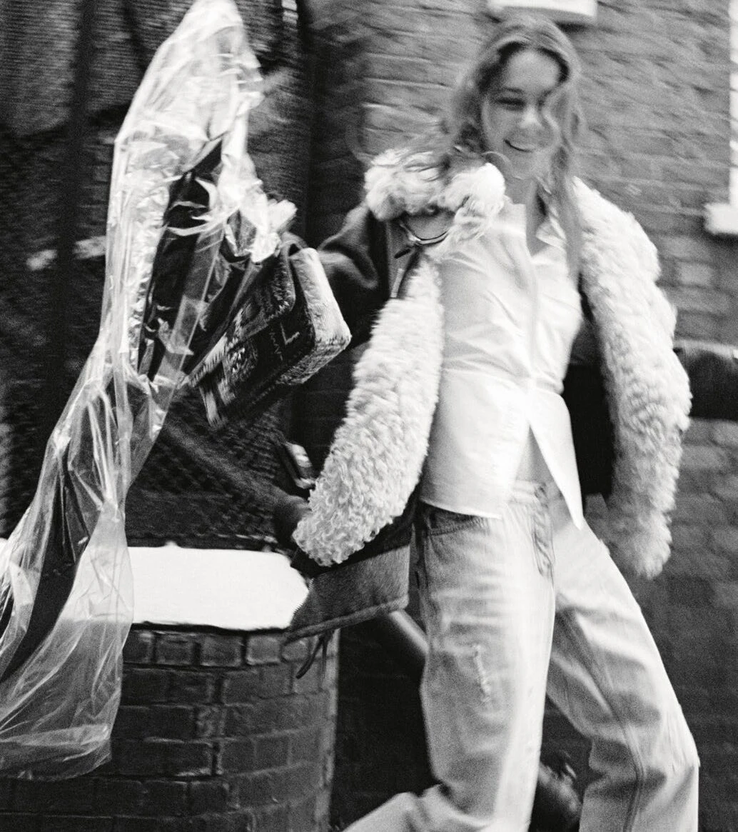 Black-and-white street fashion portrait with a white shirt and feathered coat