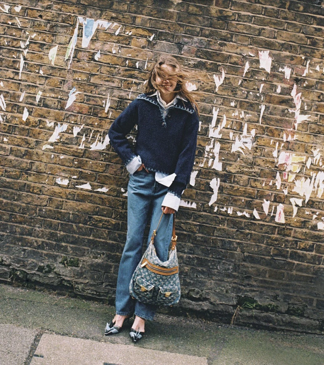 Fashion portrait in a navy jumper and jeans against a brick wall