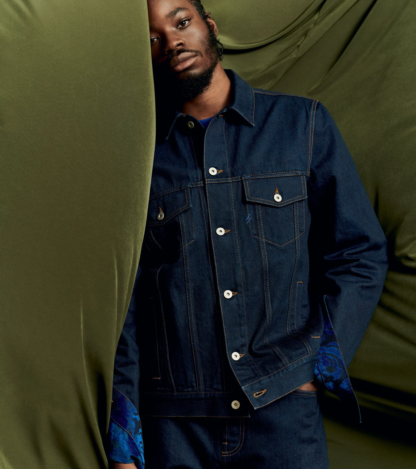 A dark denim jacket against a draped green backdrop