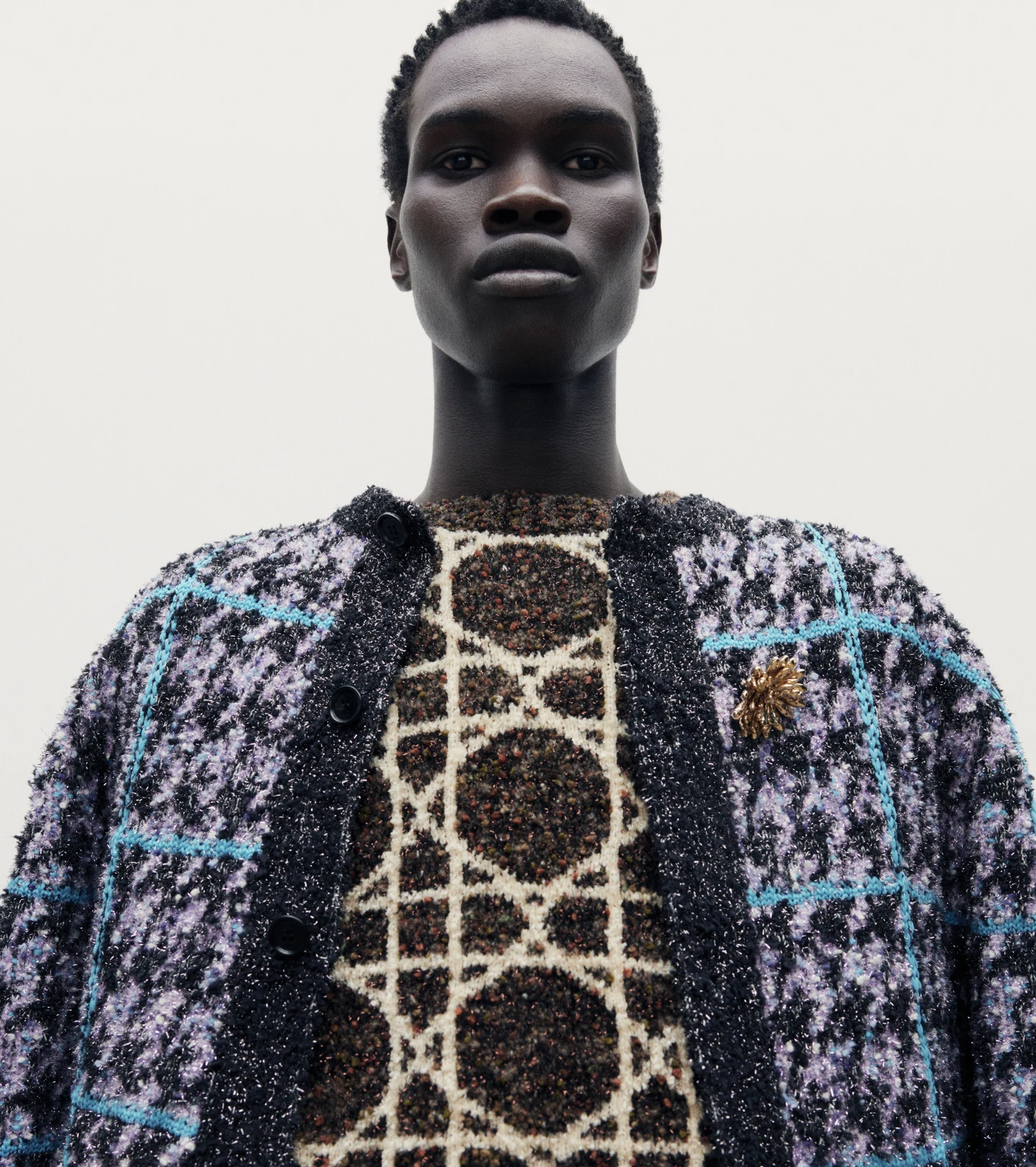 A model in a patterned jacket photographed against a pale background