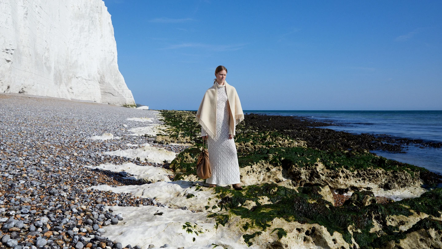 A pale outfit on a rocky beach beneath white cliffs