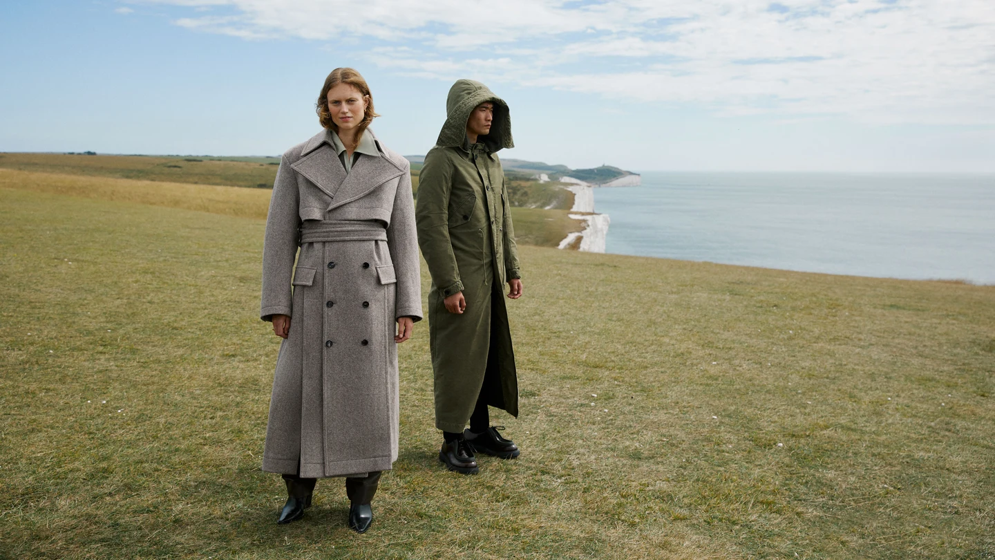 Two models in long coats beside the coast
